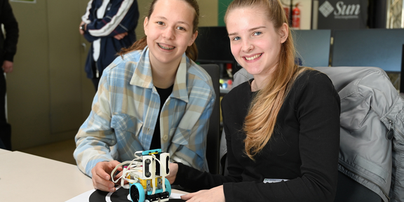 Zwei Schülerinnen präsentieren einen kleinen Roboter