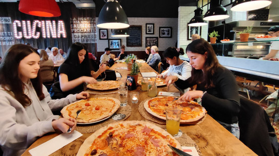 An einem langes Tisch sitzen die vier MinTU Teilnehmerinnen und essen ihre Pizzen. 