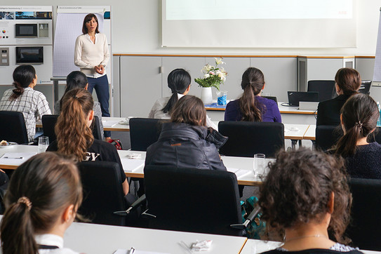 Eine Frau hält einen Votrag vor Studentinnen