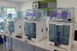 Vier 3D-Drucker der Marke Ultimaker auf einem Tisch mit Namensschildern 'Dimitri', 'Diego' und 'Dany'.