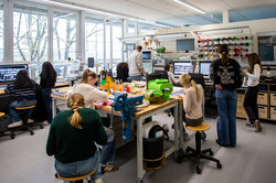 Many girls are sitting at tables in the CET's Maker Space. They are working on their creative projects.