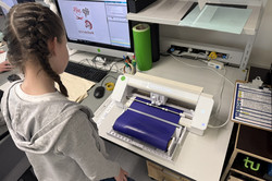A girl stands in front of a printer.