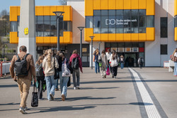 A group of girls photographed from behind. They are walking towards the TU Dortmund University cafeteria building.