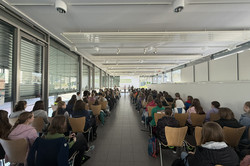The Girls' Day participants sit in rows of chairs. A presentation is shown at the front and a lecture is given. 