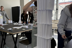 A girl stands in front of a paper tower.