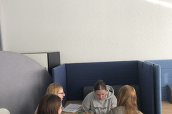 Vier Mädchen sitzen um einen Tisch, auf dem Arbeitsblätter und bunte Karten liegen.