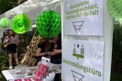 Zeltstand mit Informationsmaterial und grünen Papierdekorationen im Freien bei einem Sommerfest.