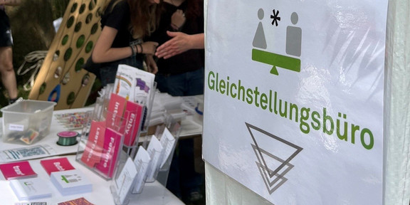 Zeltstand mit Informationsmaterial und grünen Papierdekorationen im Freien bei einem Sommerfest.