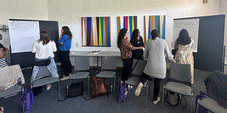 Workshopsituation, junge Frauen diskutieren vor Pinnwändern