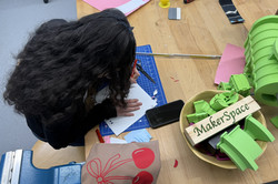 A girl bends over a sheet of paper and writes something. 