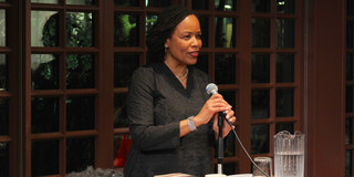 Saidiya Hartman holds a microphone and gives a keynote speech at a lectern.