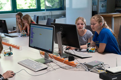 Mädchen sitzen am Bildschrim und programmieren