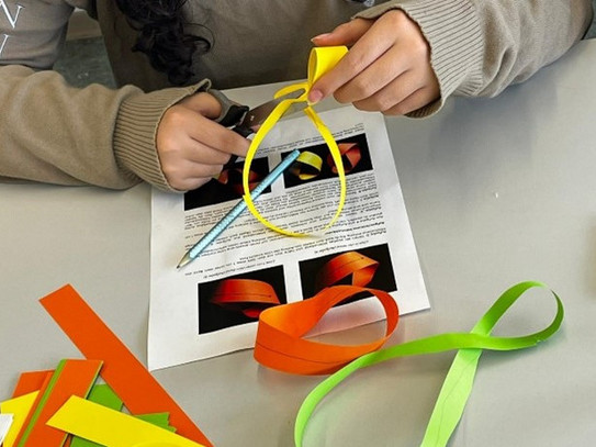 Eine MinTU-Teilnehmerin forscht am Möbius-Band, indem sie versucht, dieses der Länge nach durchzuschneiden.