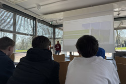 Three boys, photographed from behind, listen to a lecture.