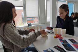 Zwei Mädchen sitzen an einem Tisch mit Pappbechern vor sich