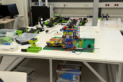 Auf einem Tisch steht ein großes Modell, gebaut aus Lego, dass ein Logistiksystem darstellt. 