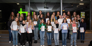 Eine Gruppe Schülerinnen stehen auf einer Treppe und halten ihr Zertifikat in den Händen.