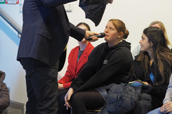 Ein älterer Mann hält eine Fledermaus-Handpuppe und spricht in ein Mikrofon vor einer Gruppe sitzender junger Menschen bei der Veranstaltung MinTU.
