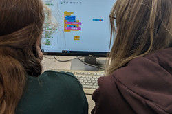 Zwei Mädchen sitzen vor einem Computer. Auf dem Bildschirm ist das Programm zu sehen. 