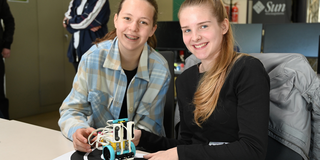 Two schoolgirls present a small robot