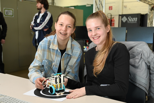 Two schoolgirls present a small robot