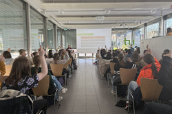 The Girls' Day participants sit in rows of chairs and listen to the welcome presentation.