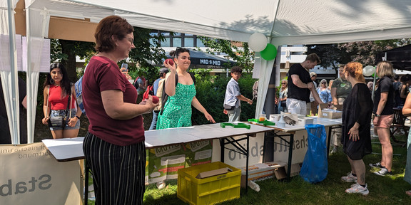 Am Sommerfest-Stand werfen Besucherinnen und Besucher Dosen mit Socken ab