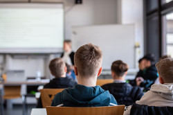 Jungs sitzen in einem Seminarraum und hören einem Vortrag zu. 