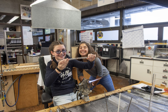 Two girls are in a workshop and enjoy working together.