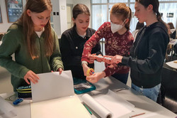 Four girls make house models with paper and glue