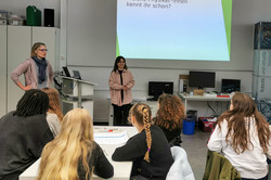 Two female scientists give a lecture to a group of schoolgirls. Title: ‘Which female physicists do you already know?’
