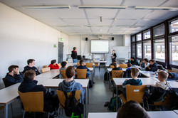 A group of boys sit in a seminar room and listen to a lecture.