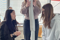 Ein Mädchen steht auf einem Stuhl, um einen sehr hohem Turm zu bauen