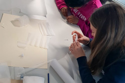 Two girls make houses with paper and sticky tape.