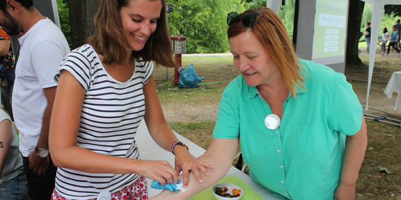 A woman sticks a peel-off tattoo on the forearm of another woman