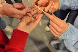 Four hands meet in the centre, a spaghetti balances on the fingers.