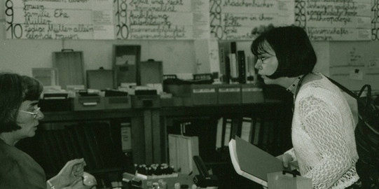 Two women stand opposite each other and talk to each other in the new women's archive 