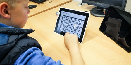 Ein Junge sitzt mit einem Tablet und lernt eine App kennen
