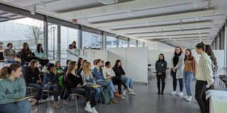 Studentinnen stehen vor einer Gruppe von Schülerinnen