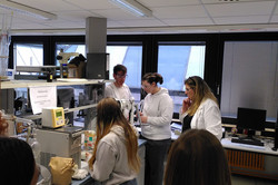 Several girls stand around the work surface and the press. 