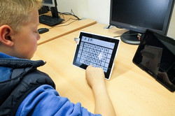 Ein Junge sitzt mit einem Tablet und lernt eine App kennen