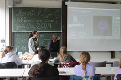 GD24_Physik Schülerinnen sitzen in einem Raum und hören einen Vortrag
