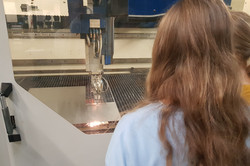 Blick über die Schuler einer Schülerin auf eine Maschine