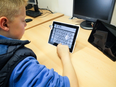 Ein Junge sitzt mit einem Tablet und lernt eine App kennen